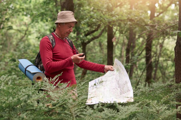 Coordenação e navegação na floresta. Imagem do homem segurando o mapa da bússola e papel nas mãos, encontrar o caminho certo na madeira