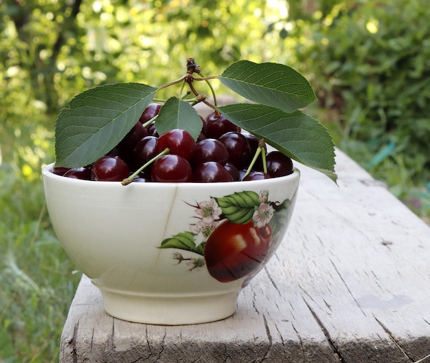 Copa blanca llena de cerezas maduras sobre la mesa