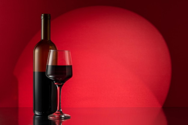 Copa y botella de vino tinto sobre fondo rojo Concepto de vino