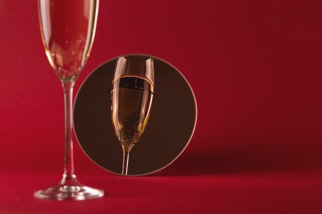 Copa de champán con reflejo en un pequeño espejo redondo sobre un rojo