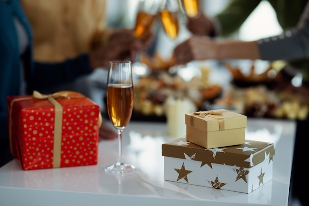 Copa de champán y regalos de Navidad en la mesa en la fiesta de la oficina