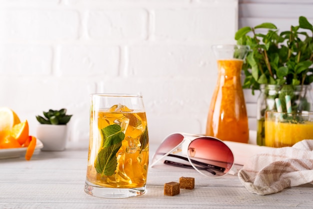 Copa de cóctel con hielo, menta y jengibre en un fondo de madera blanco