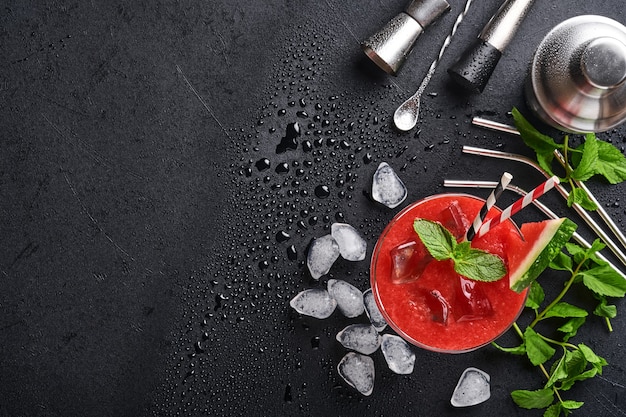 Copa de cóctel Margarita de sandía con menta y hielo. Bebidas refrescantes de verano en vasos sobre mesa negra. Concepto de alimentación saludable en verano.