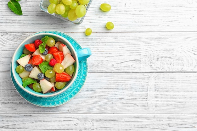 Copa com deliciosa salada de frutas na mesa de madeira