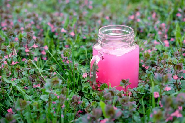 Copa de cristal de batido rosa o kissel verde hierba con flores de color rosa