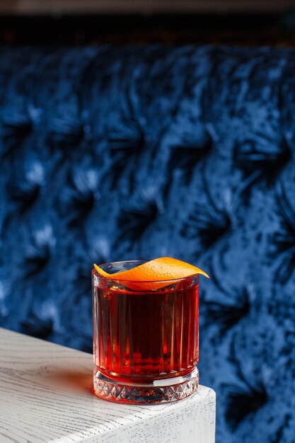 Copa de cristal con cóctel alcohólico frío brillante decorado con ralladura de naranja Fondo borroso Cóctel Negroni