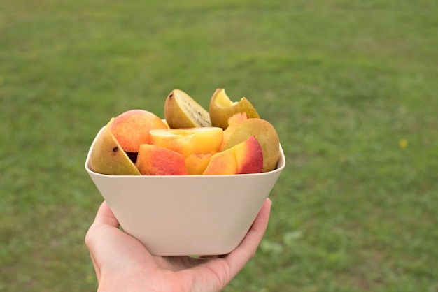 Copa de frutas fica em uma mesa de madeira.