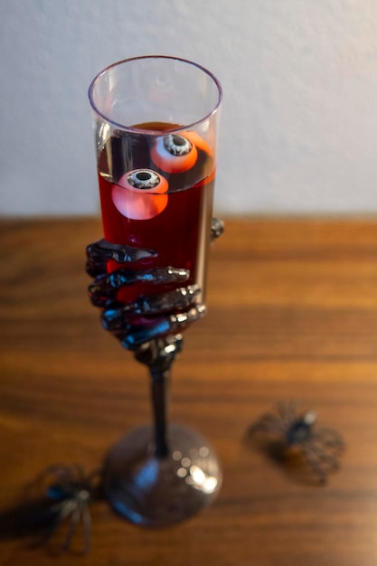 Copa de mano esqueleto con vino tinto y globos oculares en el interior. Bebida mágica aterradora. concepto de halloween
