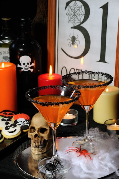 Copa de martini cítrico decorado con azúcar negra sobre la mesa en honor a Halloween