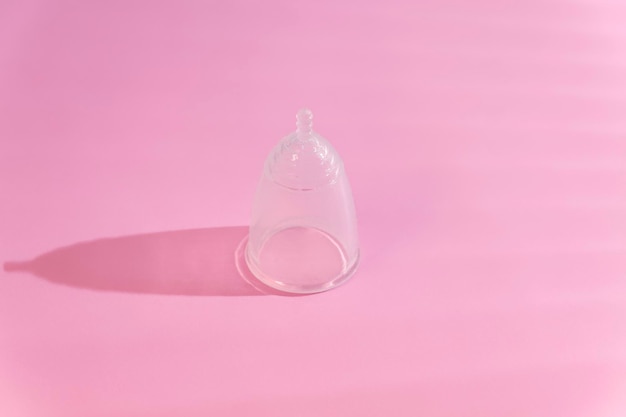 Copa menstrual ecológica sobre fondo rosa con sombras creativas