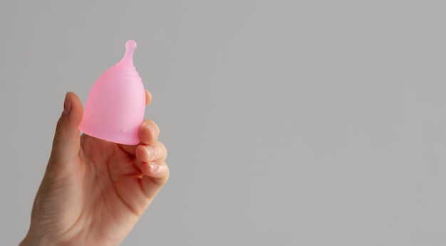 Copa menstrual en la mano de una mujer sobre un fondo blanco aislado Alternativa reutilizable a las toallas y tampones durante la menstruación y en días críticos Lugar para su diseño o maqueta