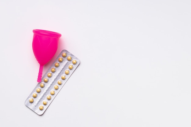 Copa menstrual y píldoras anticonceptivas orales vista superior