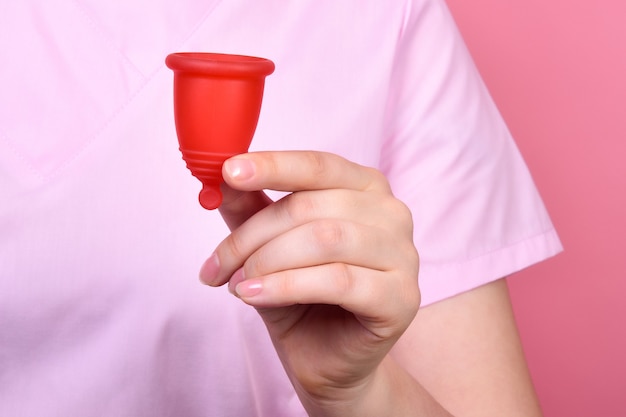 Copa menstrual de silicona roja en la mano de una doctora closeup