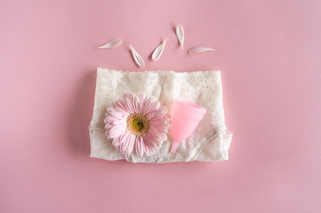 Copa menstrual de silicona Salud de la mujer e higiene alternativa Copa con flor sobre fondo rosa Alternativas cero residuos