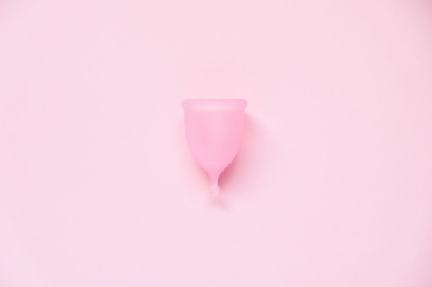 Copa menstrual sobre fondo rosa. Producto de higiene femenina alternativa durante el periodo. Concepto de salud de la mujer.