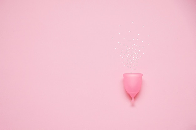 Copa menstrual sobre fondo rosa. Producto de higiene femenina alternativa durante el periodo. Concepto de salud de la mujer.