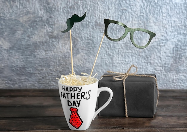 Foto copa con palabras feliz día del padre y caja de regalo en mesa de madera