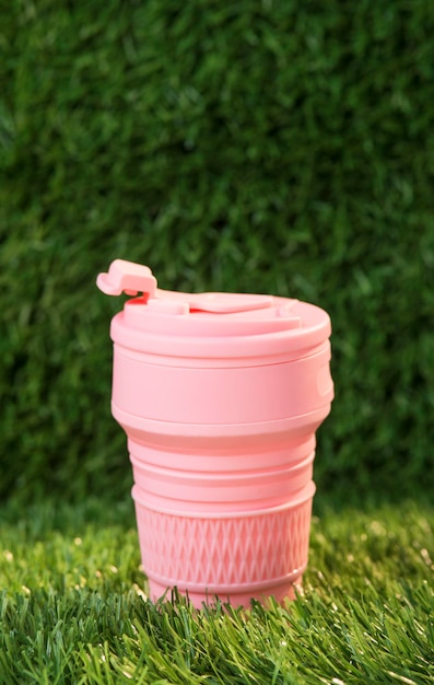 Copa de silicona plegable rosa moderna sobre el fondo de la naturaleza verde. termo reutilizable