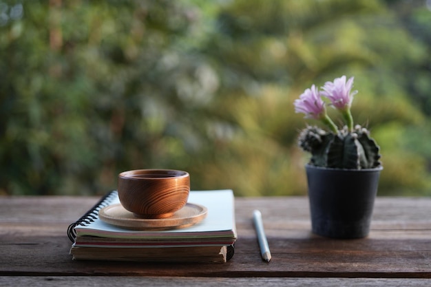 Copa de té de barro y flor de cactus rosa en una mesa de madera