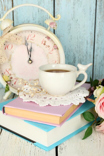 Copa de té con libros y flores sobre un fondo de madera