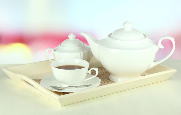 Copa de té con pasteles en una bandeja de madera en la mesa en la habitación