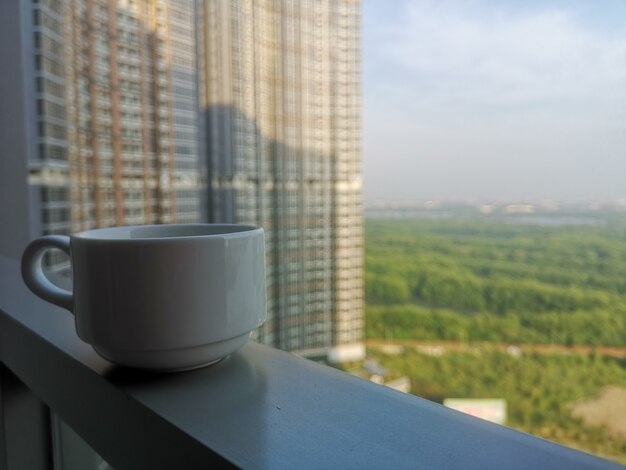 Copa de vidrio blanco en el balcón con el cielo y el fondo del hotel del edificio