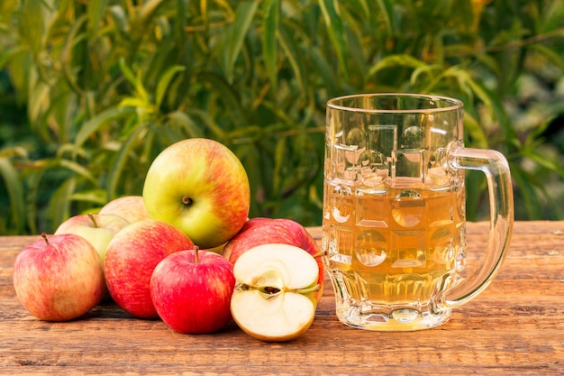 Copa de vidrio de sidra de manzana y manzanas cosechadas sobre tablas de madera con hojas de manzano en el fondo. Solo recogí frutas. Bebidas orgánicas