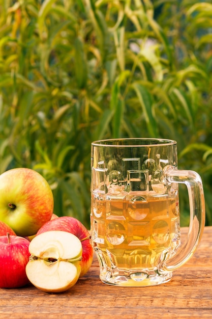 Copa de vidrio de sidra de manzana y manzanas cosechadas sobre tablas de madera con hojas de manzano en el fondo. Solo recogí frutas. Bebidas orgánicas