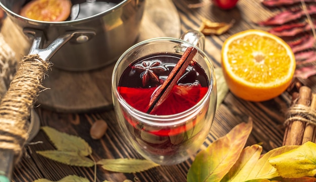 Copa de vidrio con vino caliente decorado con anís estrellado de canela y naranja sobre una mesa de madera Concepto de una bebida tradicional de calentamiento