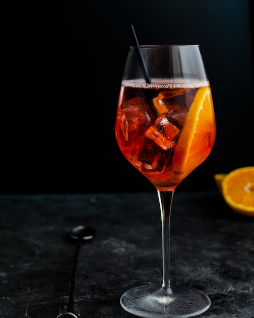 Copa de vino con aperol spritz, cóctel alcohólico italiano en la oscuridad