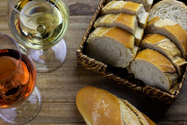 Copa de vino blanco y copa de vino rosado en una mesa de madera con una cesta de pan vista de arriba hacia abajo