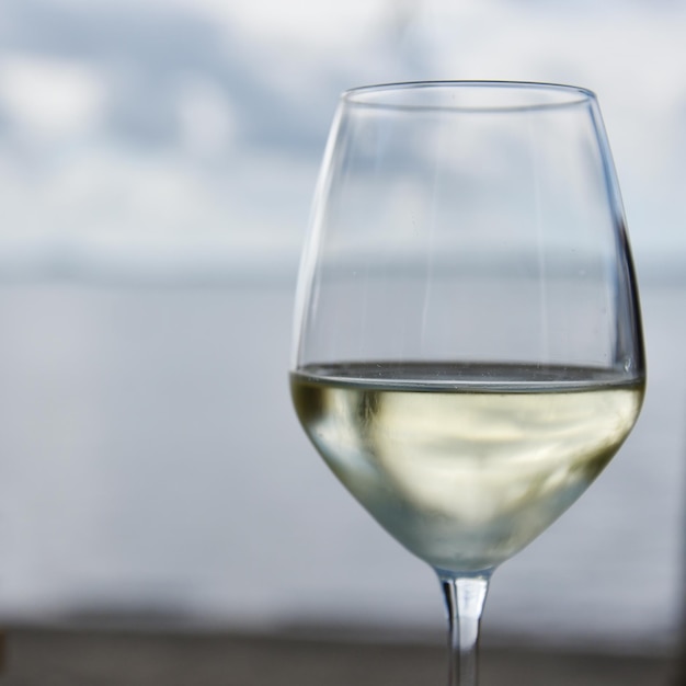 Una copa de vino blanco con lago o mar al fondo