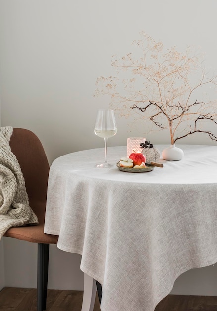 Una copa de vino blanco, una manzana, un ramo decorativo sobre la mesa en una acogedora sala de estar
