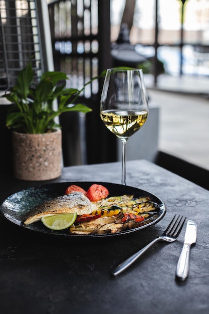 Una copa de vino blanco y un plato de pescado con una copa de vino blanco.