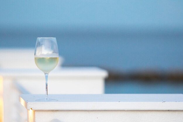 Copa con vino blanco con playa al atardecer en el fondo