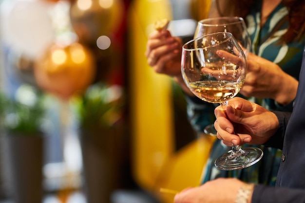 Copa con vino blanco en un primer plano de mano femenina Chica sosteniendo una copa de vino blanco