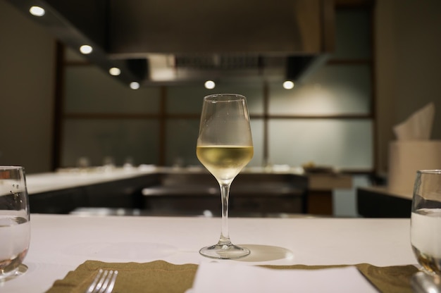 Una copa de vino blanco se sienta en una mesa frente a un restaurante.