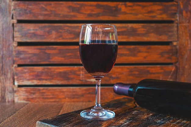 Copa de vino y botella de vino en la mesa de madera