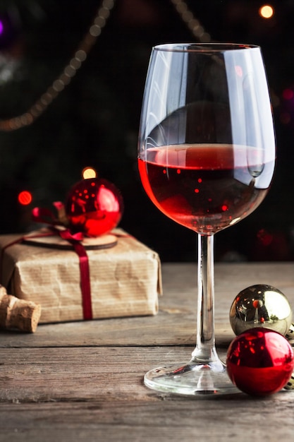 Una copa de vino con una caja de regalo de Navidad en una mesa de madera.