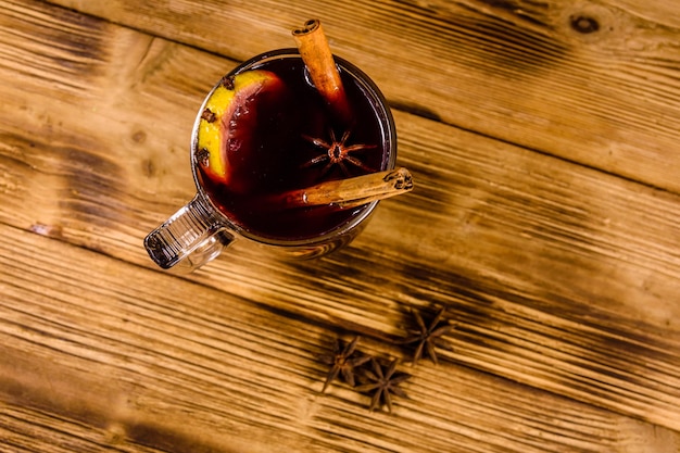 Copa de vino caliente con canela sobre mesa de madera rústica. Vista superior