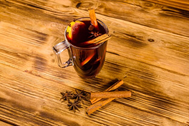 Copa de vino caliente con canela sobre mesa de madera rústica