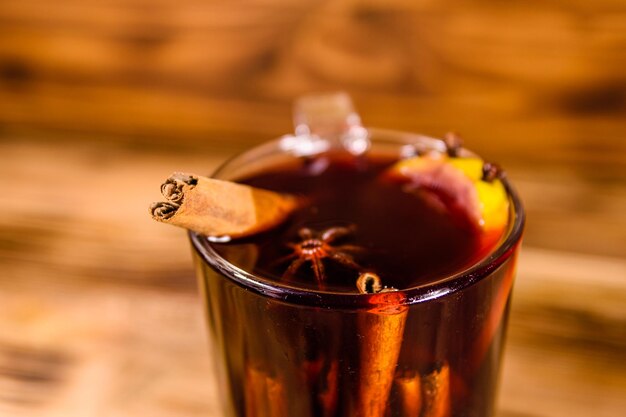 Copa de vino caliente con canela sobre mesa de madera rústica