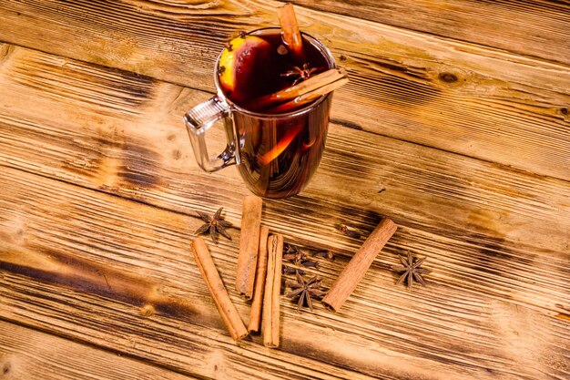 Copa de vino caliente con canela sobre mesa de madera