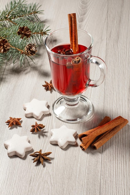 Copa de vino caliente de Navidad con especias y galletas en tablas de madera