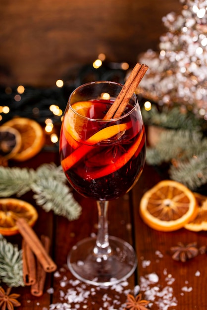 Foto una copa de vino caliente sobre la mesa de madera rodeada de adornos navideños bebida de invierno festivo