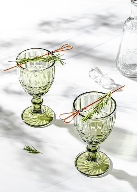 Copa de vino de cristal verde sobre fondo blanco con sombra de hojas