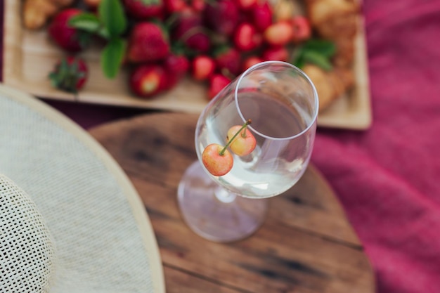 Copa de vino con dos cerezas en la bandeja de madera