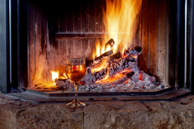 Una copa de vino junto a una chimenea en llamas.