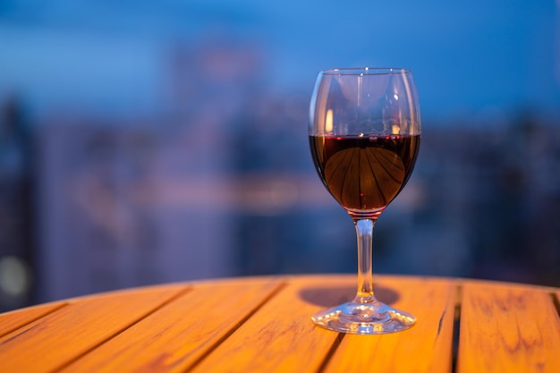 Una copa de vino en una mesa con una ciudad al fondo