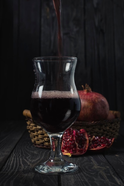 Una copa de vino o jugo de granada sobre un fondo de fruta madura en una canasta en una llave oscura